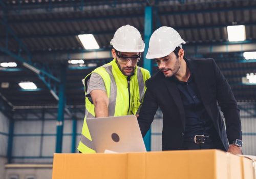 Due uomini in fabbrica al pc che si occupano di sincronizzare pianificazione e produzione